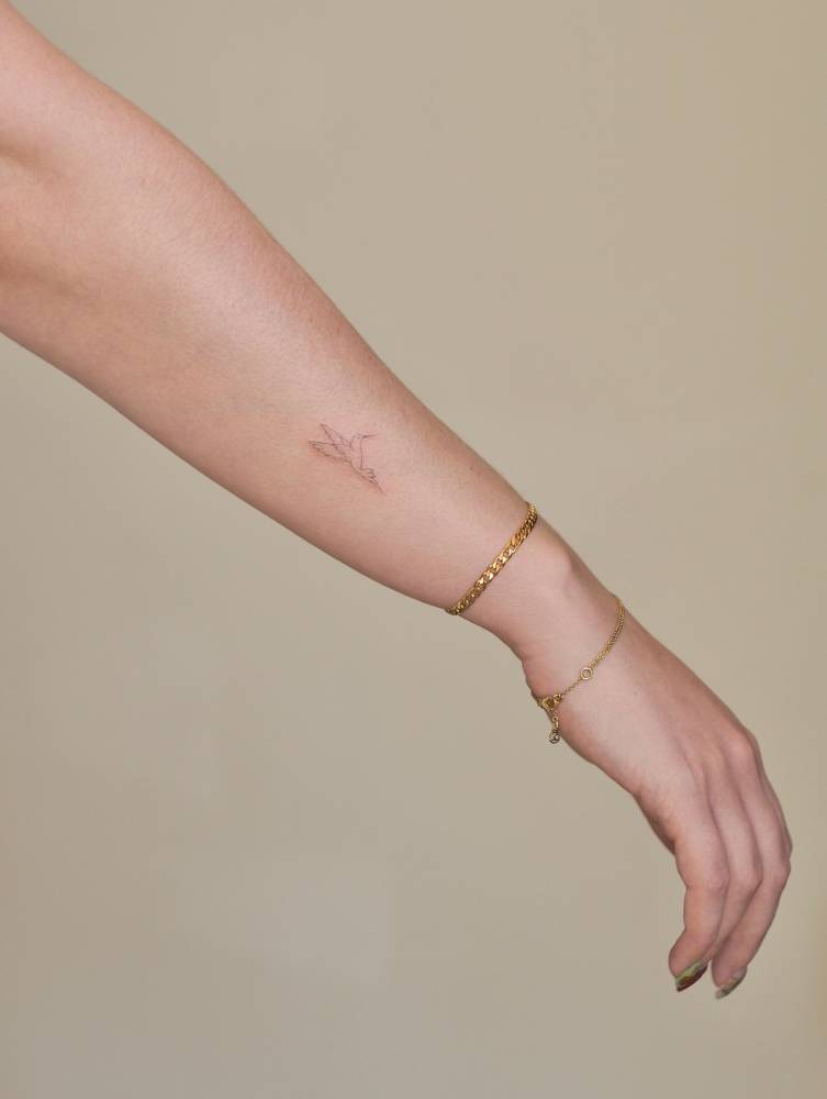 Cute hummingbird tattoo placed on the wrist, done in fine line style.