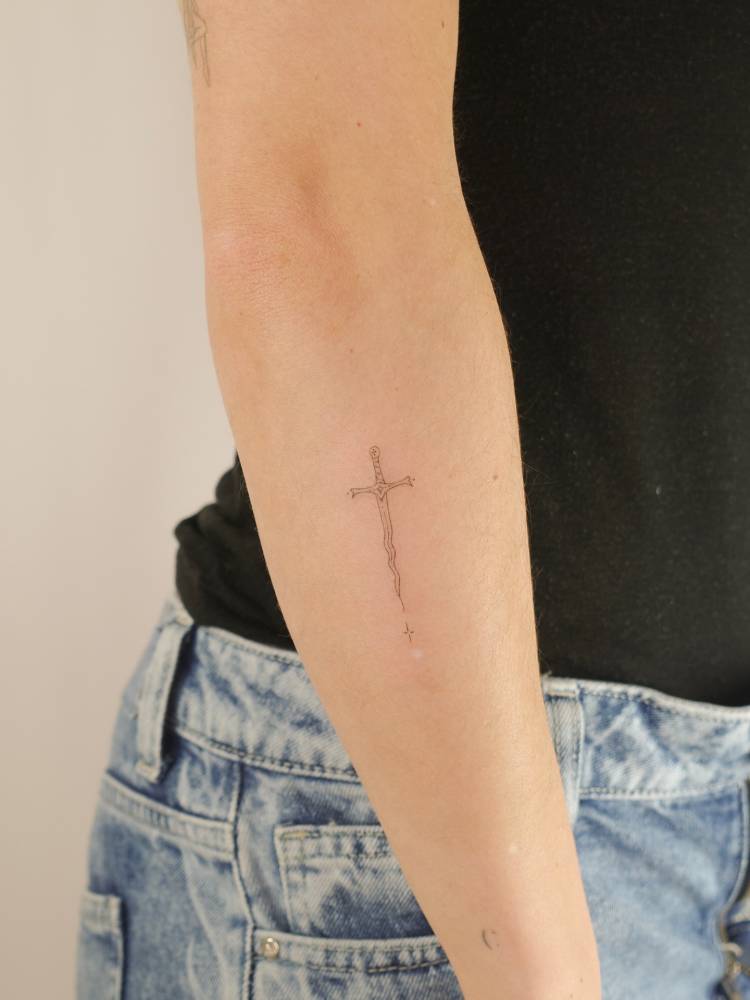 Sword tattoo located on the forearm, fine line style.