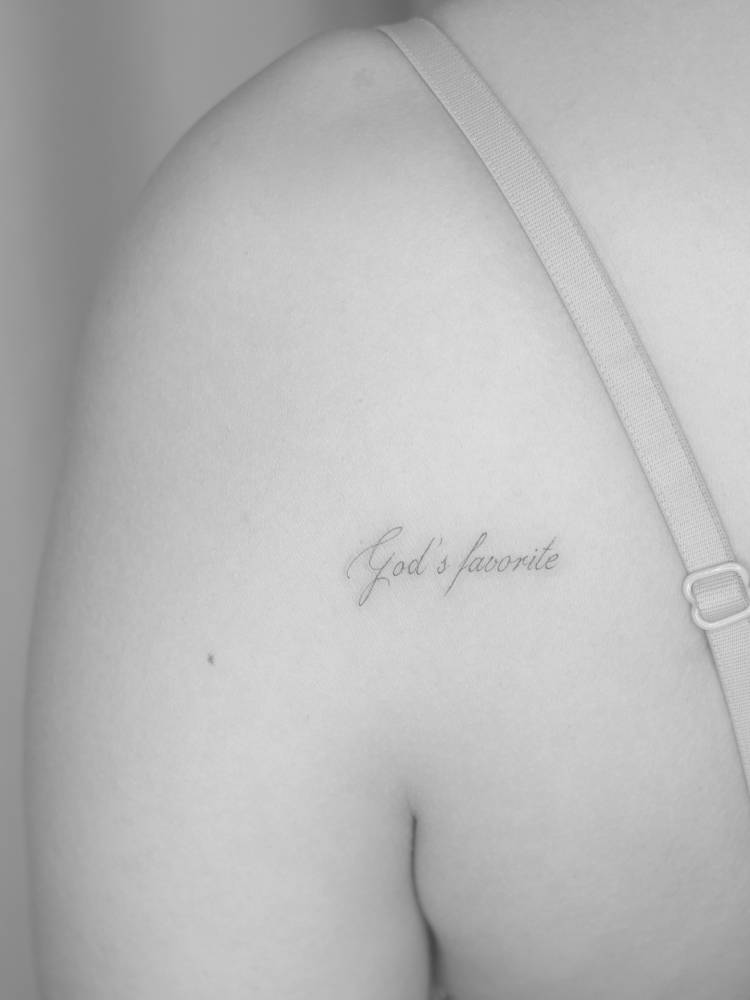 "God's favorite" lettering tattoo in handwritten font.