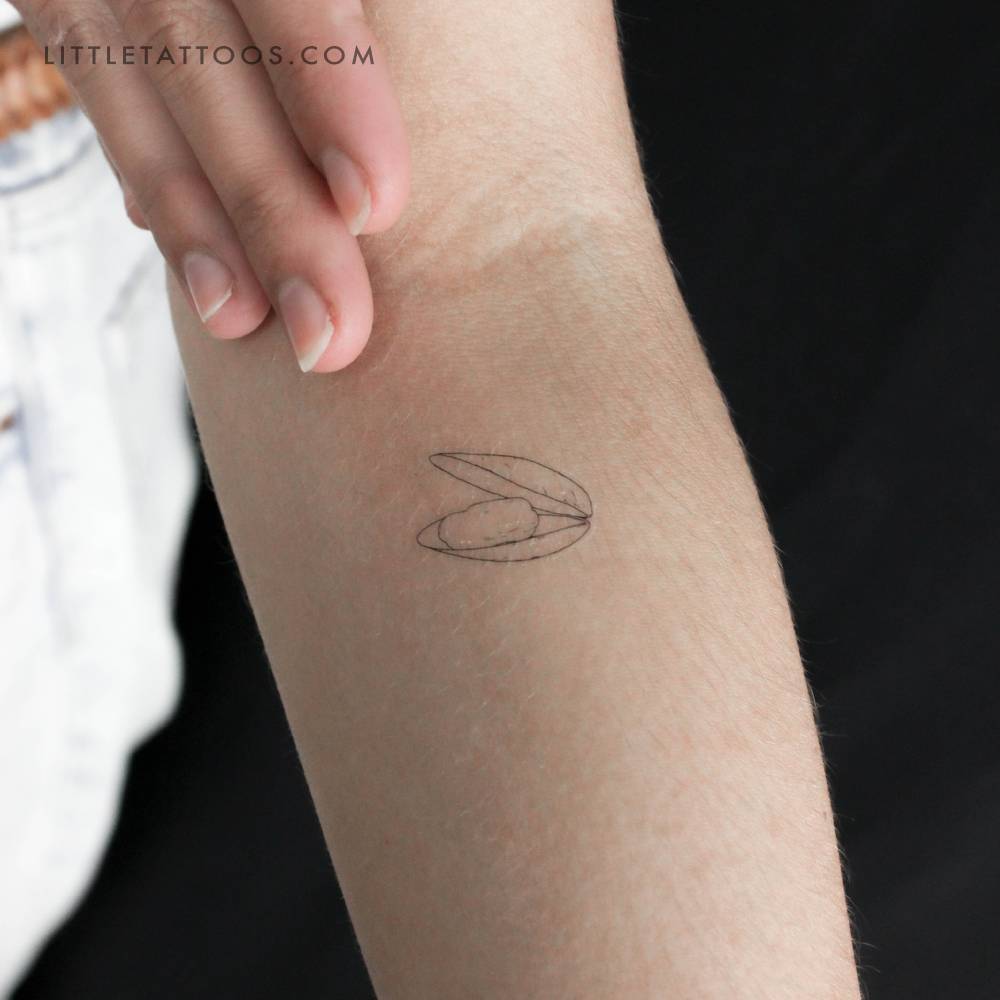 Clam temporary tattoo in fine line style located on the inner forearm.