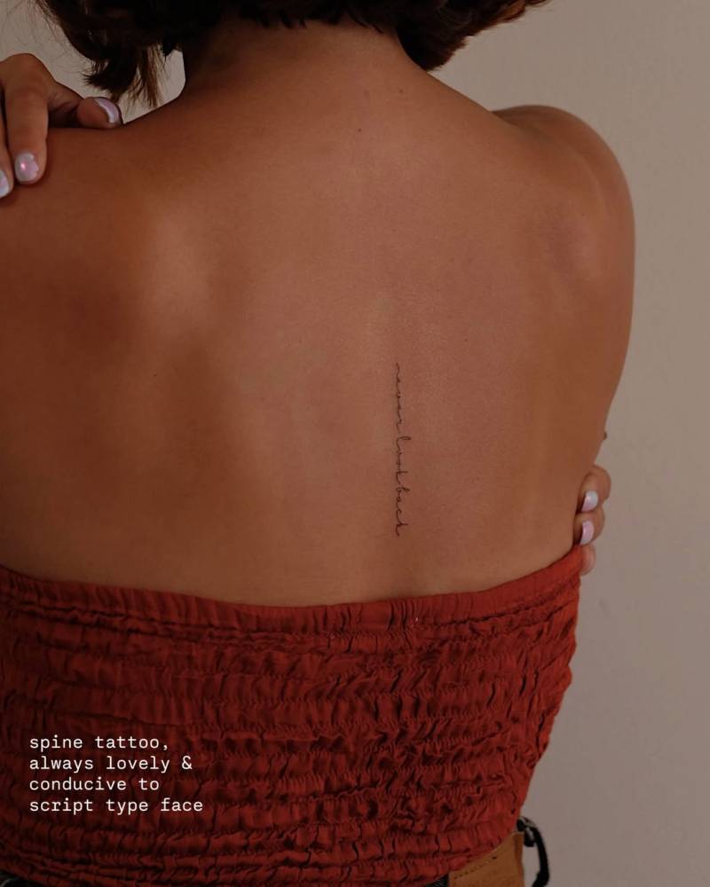 Handwritten font "never look back" lettering tattoo located on the upper back.