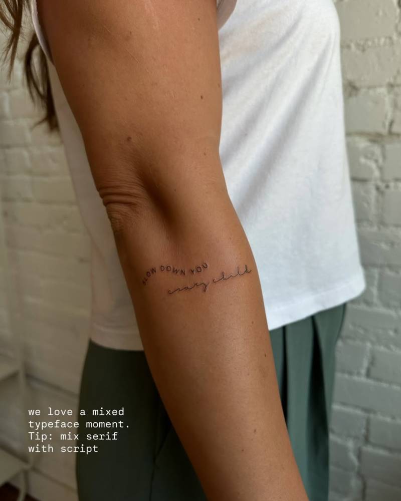 "Slow down you crazy child" lettering tattoo located on the forearm.