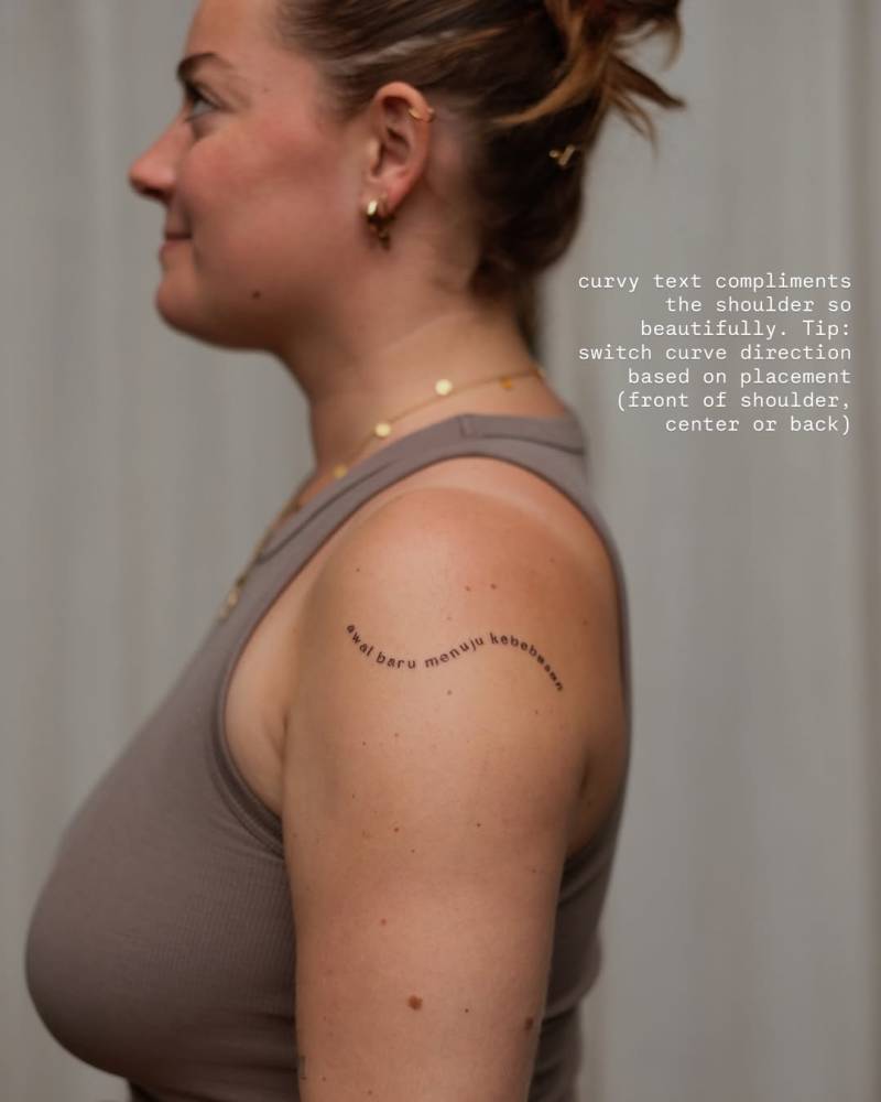 "Awal baru menuju kebebasan" lettering tattoo located on the upper arm.