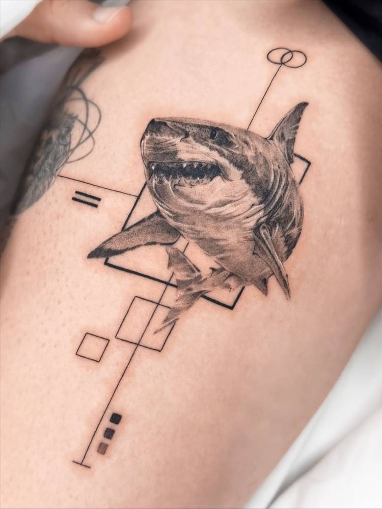 Graphic style shark tattoo located on the thigh.