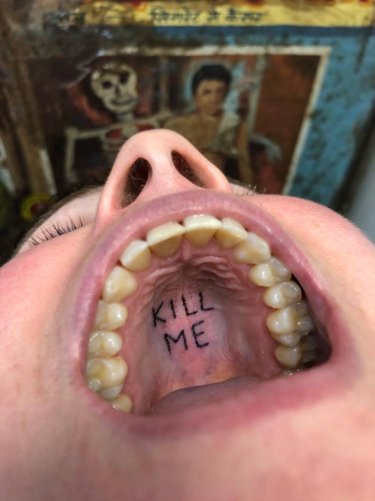 "Kill me" lettering tattoo located inside the mouth.