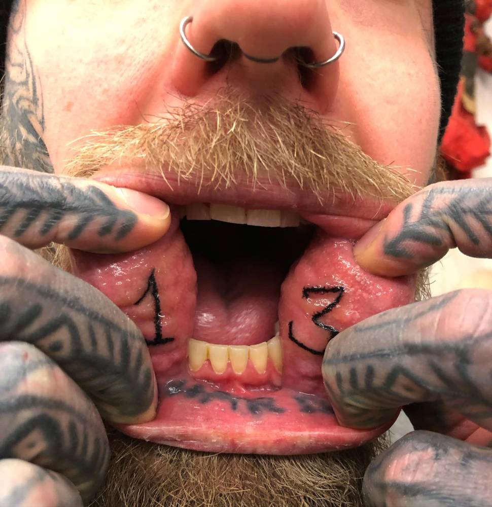 Hand poked number "13" tattoo located inside the mouth.