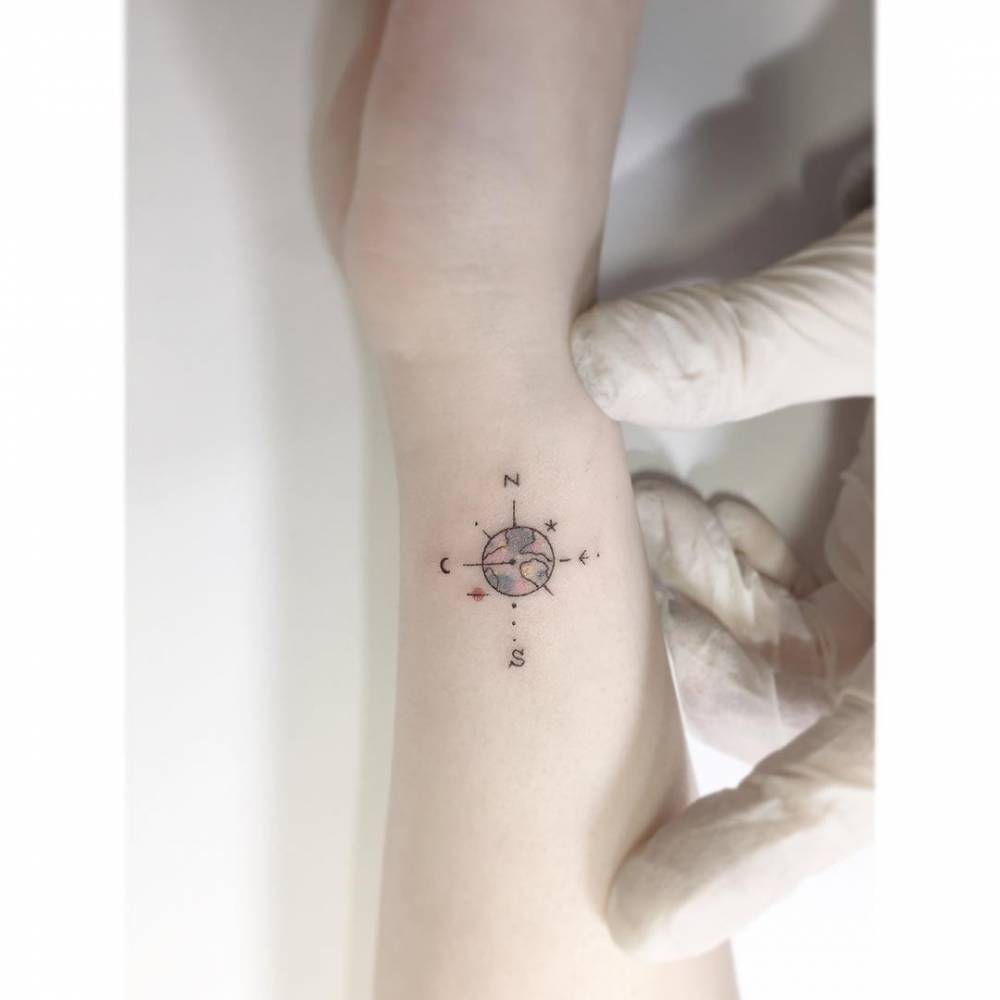 Compass rose tattoo in illustrative style placed on the wrist.