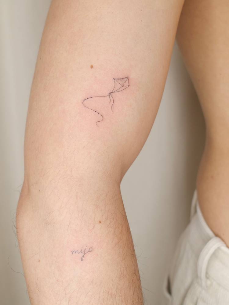 Fine line style little kite tattoo done on the upper arm.