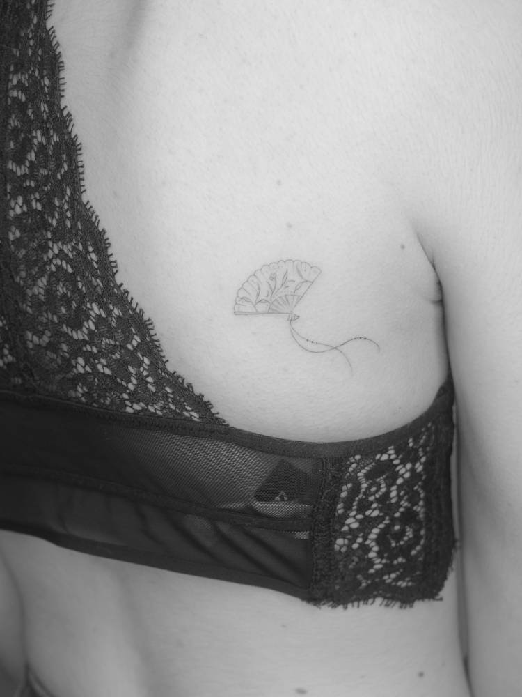 Hand fan tattoo in fine line style placed on the back.
