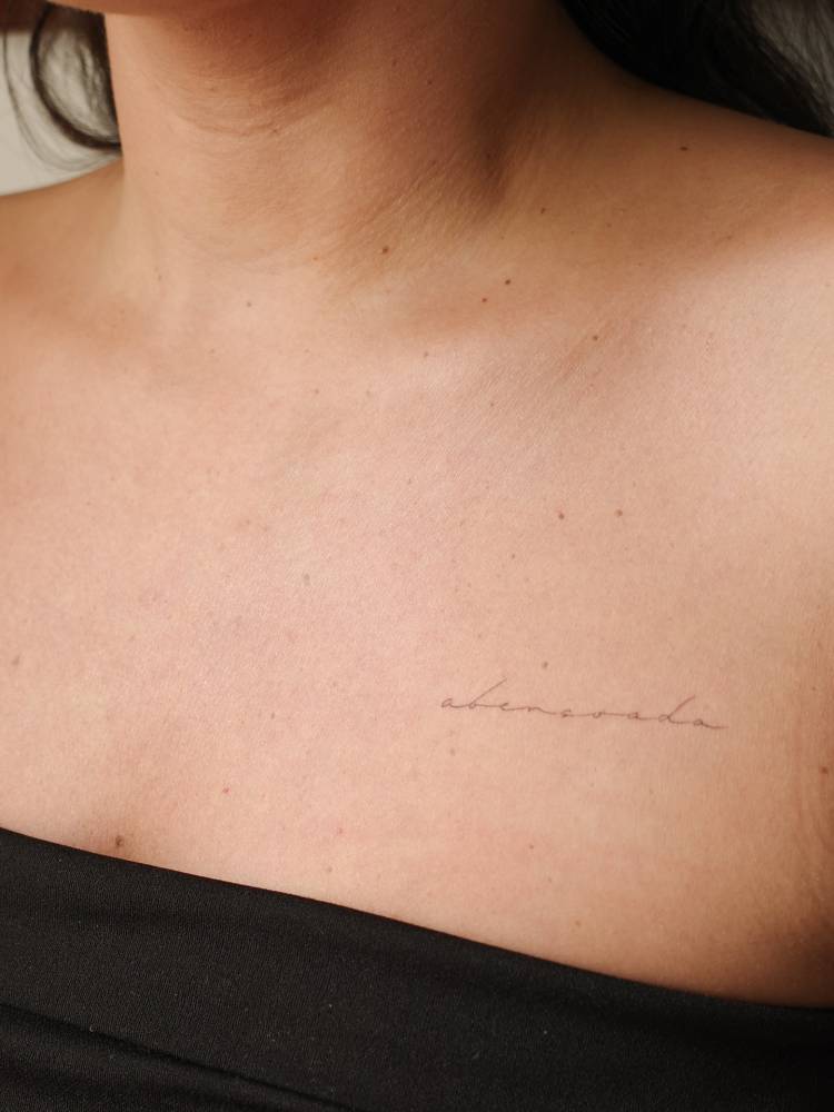 Lettering tattoo of the word "abençoada" placed on the chest.