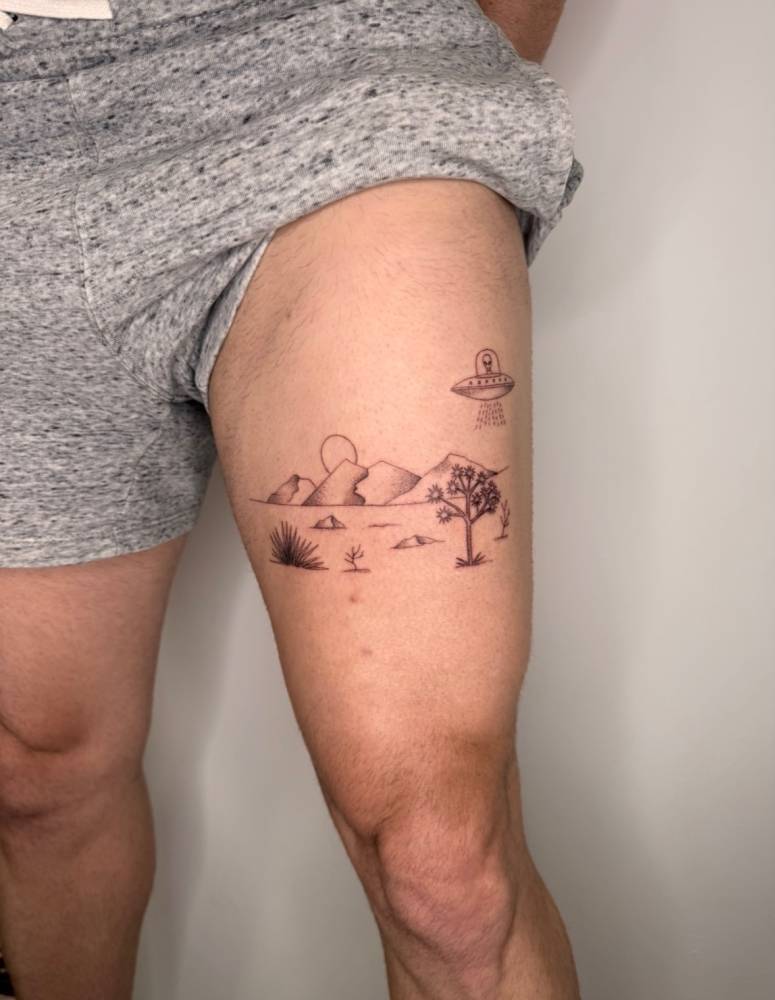Desert landscape and UFO tattoo located on the thigh.