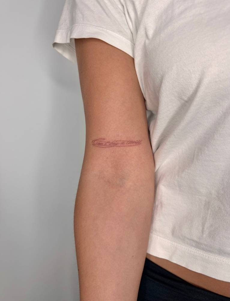 "Can't buy a thrill" lettering tattoo located on the bicep.