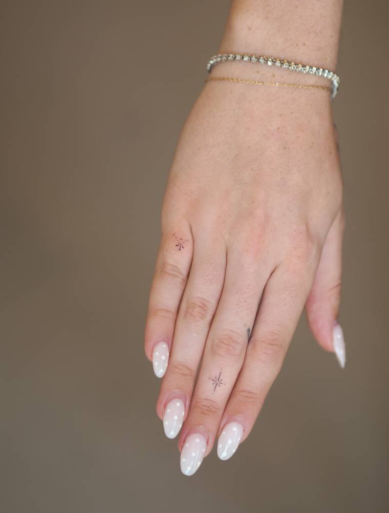 Minimalistic ornament and north star tattoos located on the fingers.