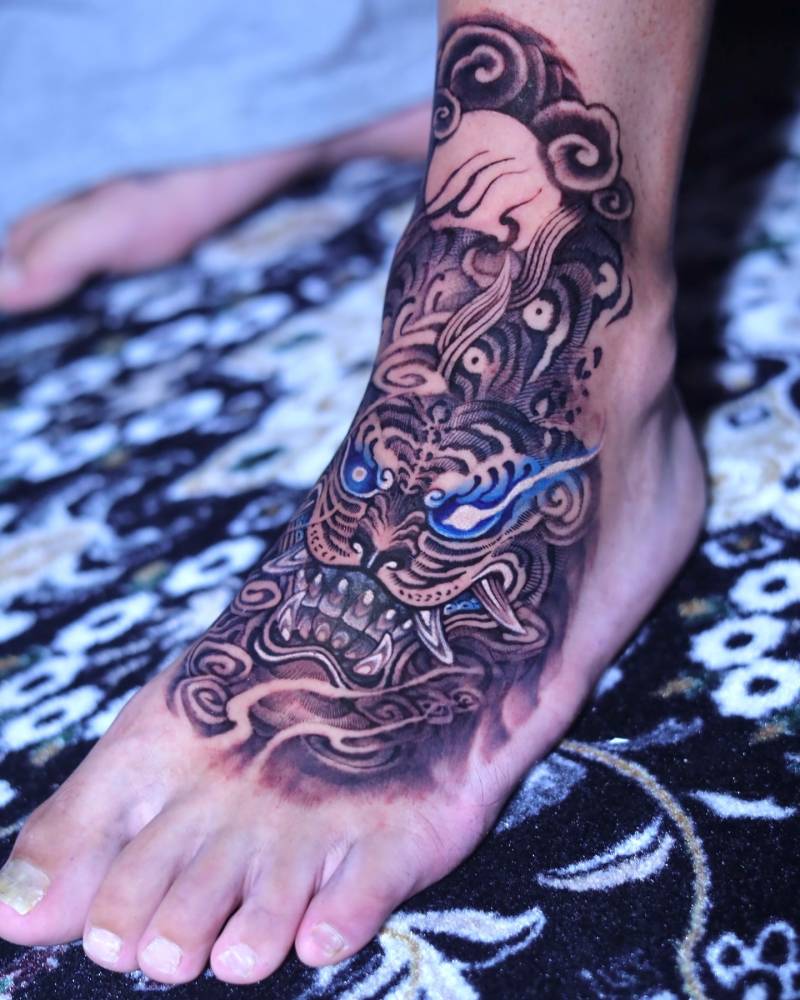 Oriental style tiger tattoo located on the foot and ankle.