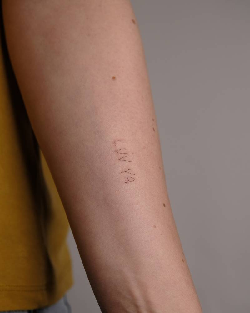 "Luv ya" lettering tatoo located on the inner forearm.