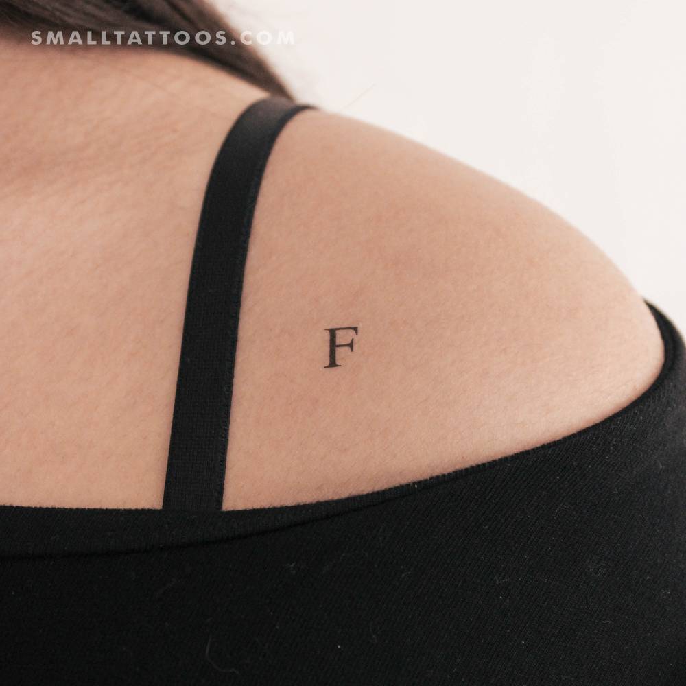 "F" uppercase serif letter temporary tattoo located on the shoulder.