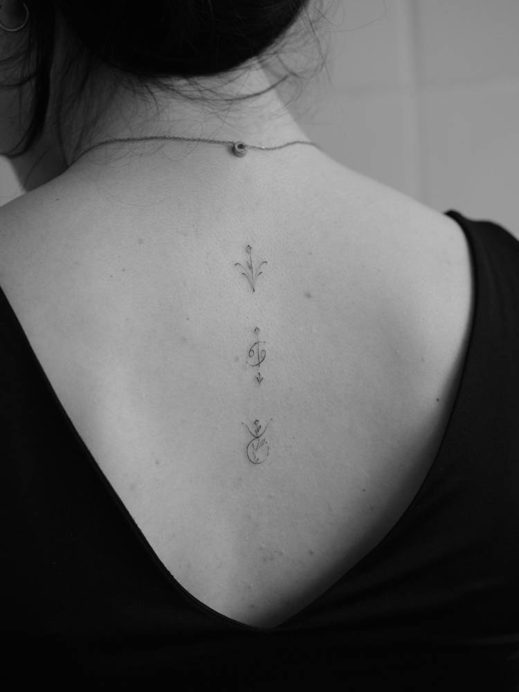 Ornaments and Cancer zodiac symbol tattooed on the upper back.