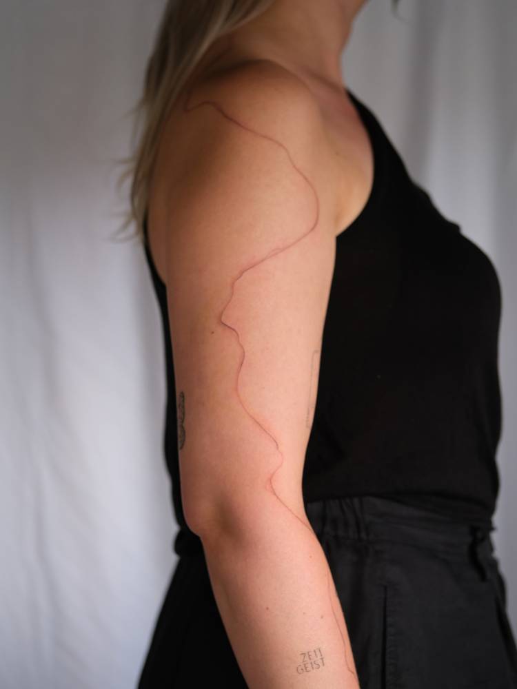 Freehand abstract line tattooed on the upper arm.