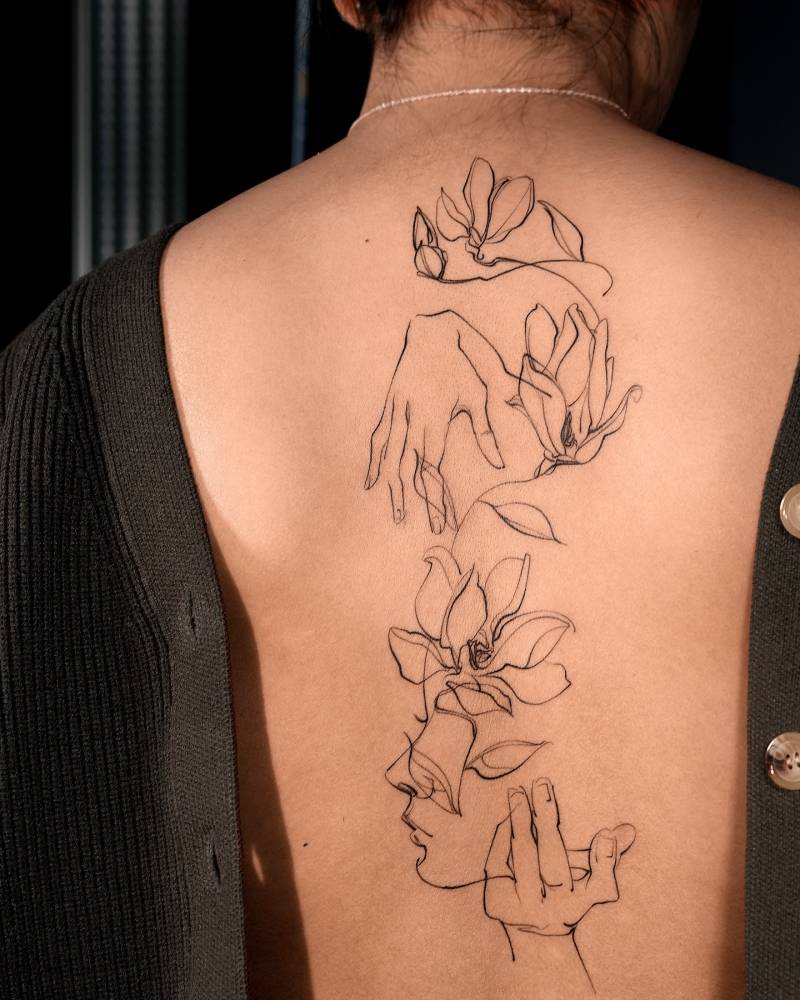 Flower head woman and magnolias tattoo located on the back.