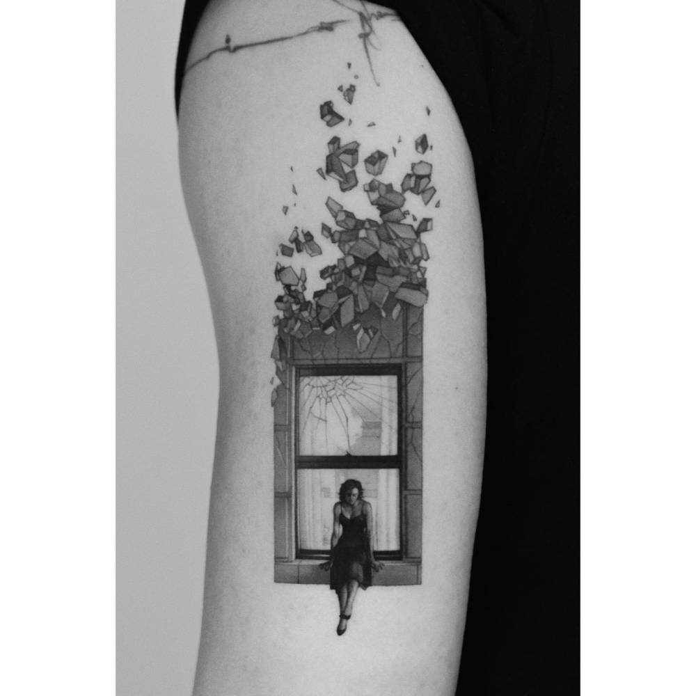 Crumbling window tattooed on the tricep, micro-realistic style.