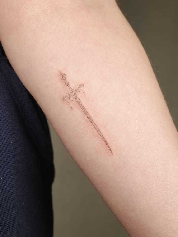 Sword tattoo in fine line style done on the inner forearm.