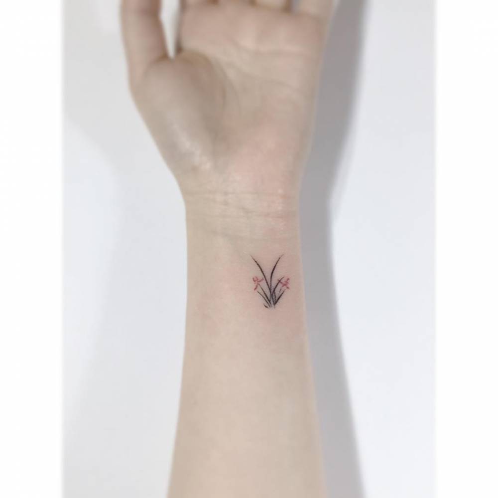 Minimalistic style orchids tattoo located on the wrist.