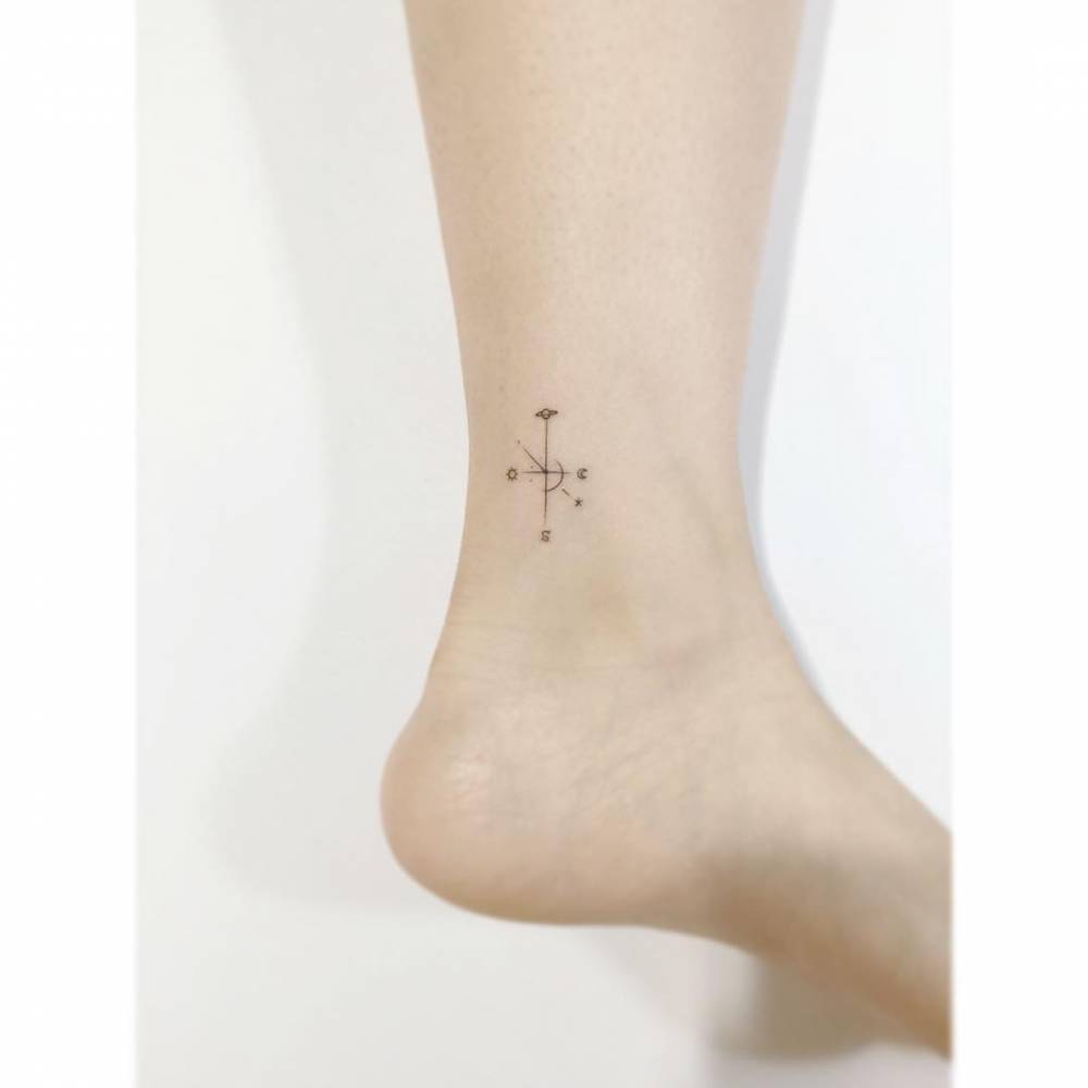 Tiny minimalistic compass rose tattooed on the ankle.