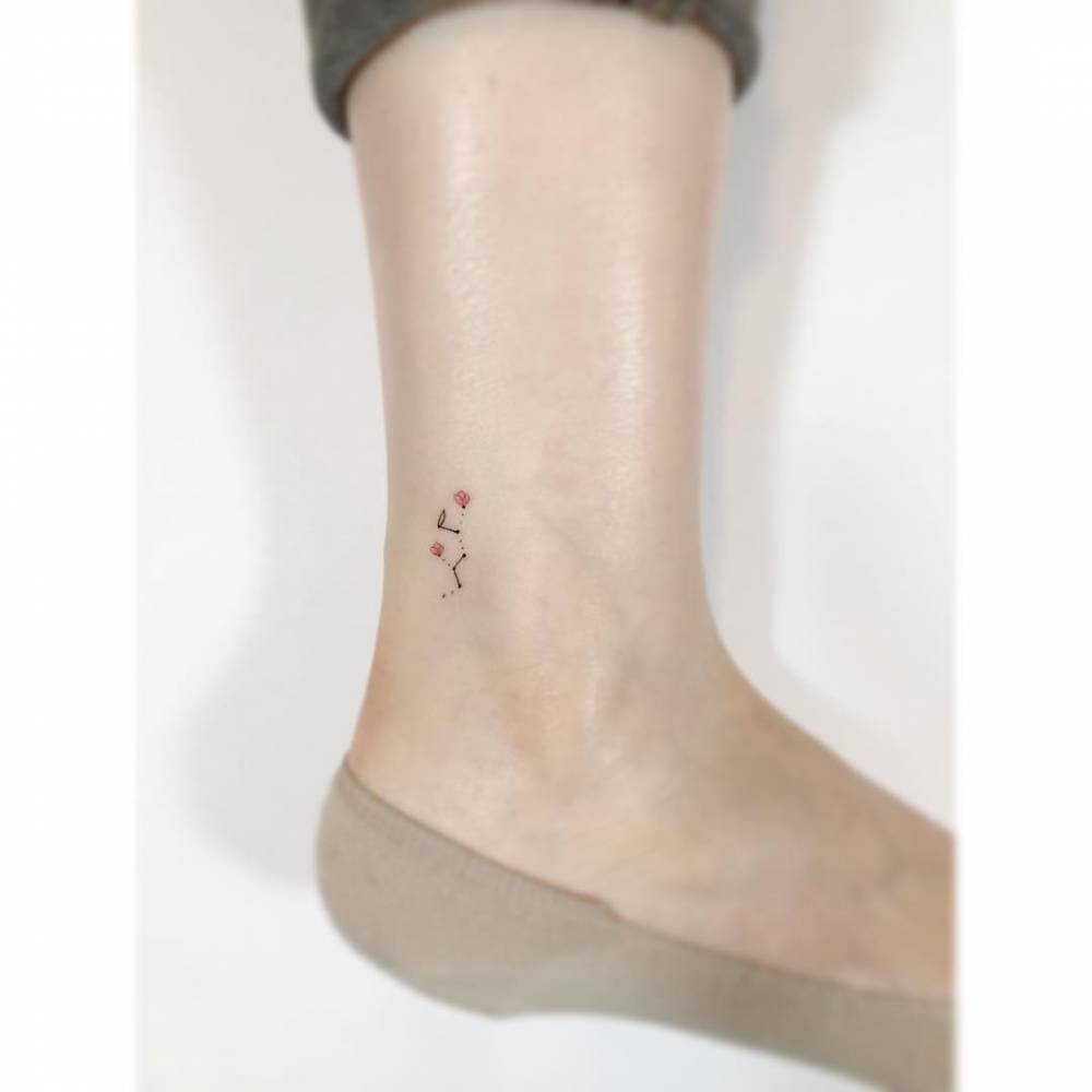 Floral Sagittarius constellation tattooed on the ankle, minimalistic style.
