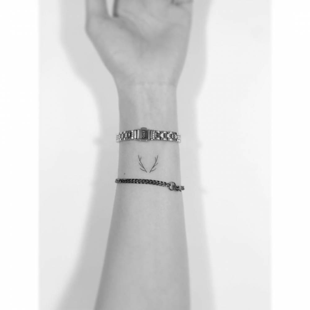 Little antlers tattoo in minimalistic style located on the wrist.