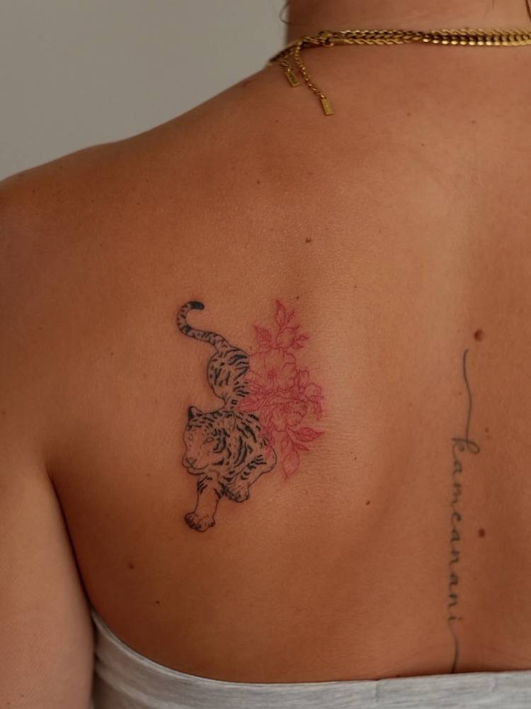 Tiger and red flowers tattoo in illustrative style located on the shoulder blade.