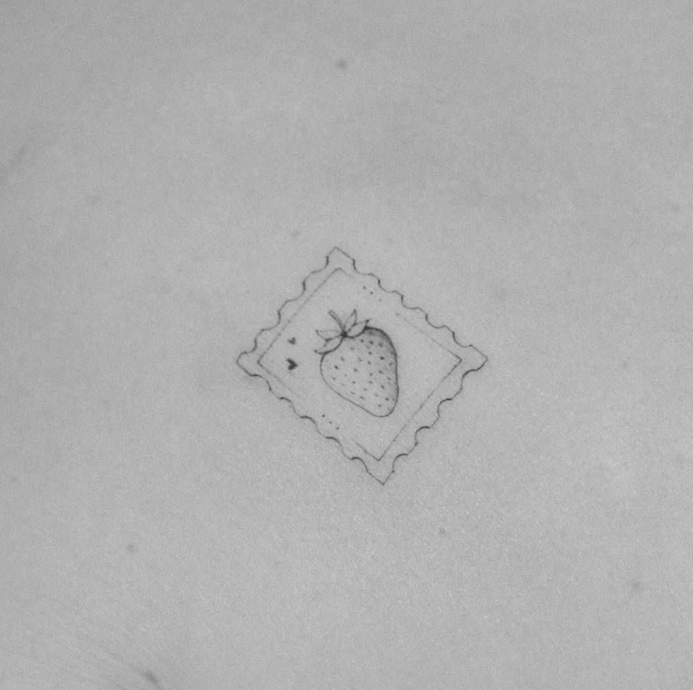 Strawberry stamp tattoo located on the back, illustrative style.