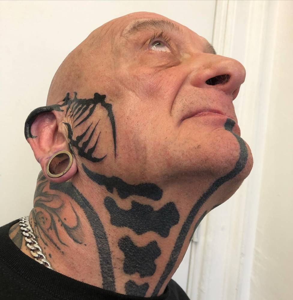 Tribal design tattoo hand poked on the face and ear.