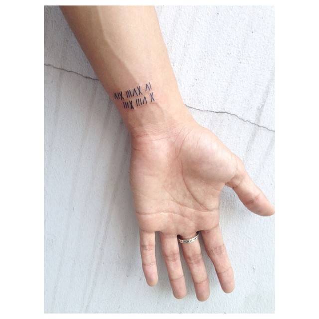 Roman numerals tattoo located on the wrist.