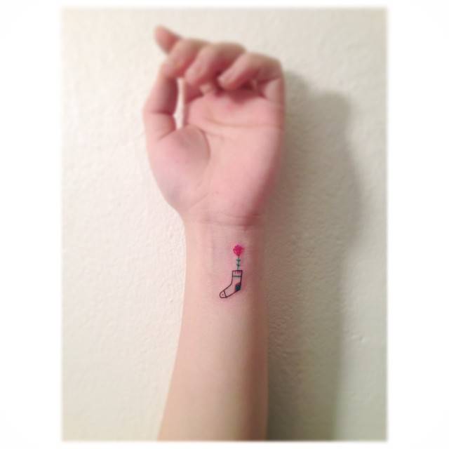 Sock and flower tattoo located on the wrist, minimalistic style.