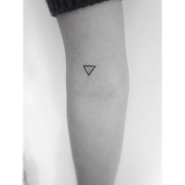 Water alchemy symbol tattoo placed on the bicep, minimalistic style.