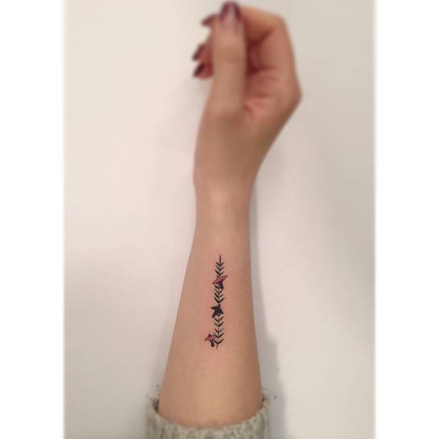 Birds on a branch tattooed on the wrist, illustrative style.