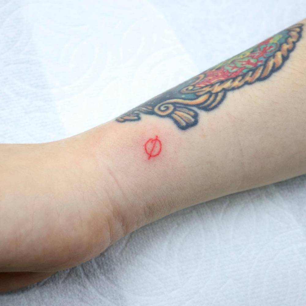 Prohibition sign tattooed on the wrist, minimalistic style.