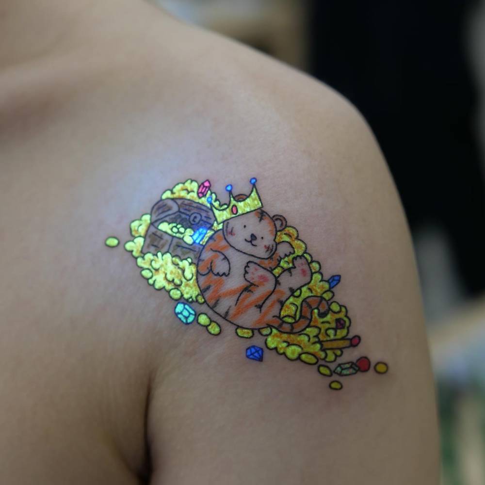 Lucky tiger tattoo in cartoon style located on the shoulder.