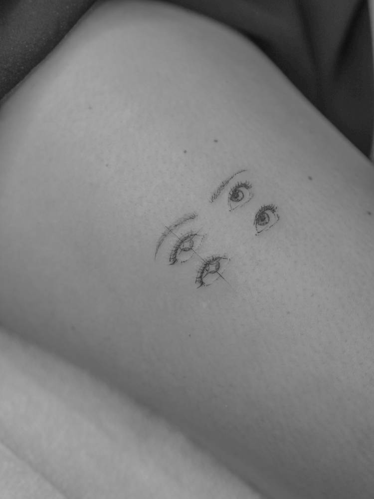 Eyes tattoo located on the thigh, done in illustrative style.