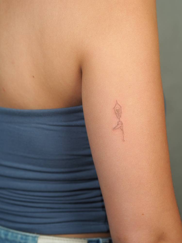 Yogini skeleton tattoo located on the upper arm, fine line style.