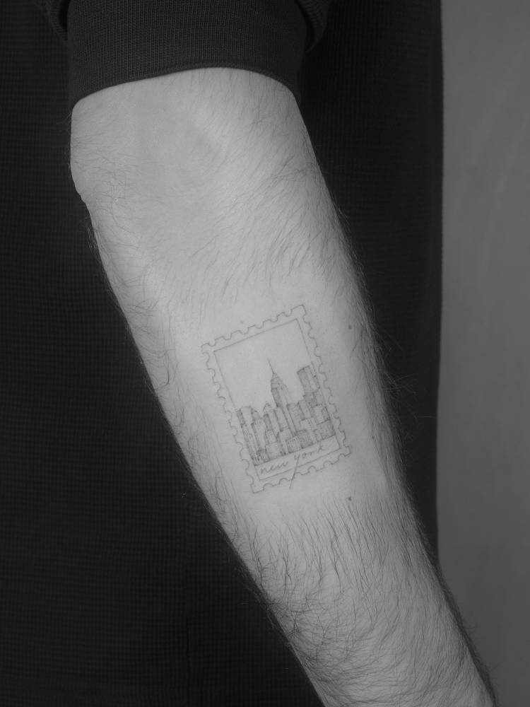Fine line style New York City skyline stamp tattoo located on the forearm.