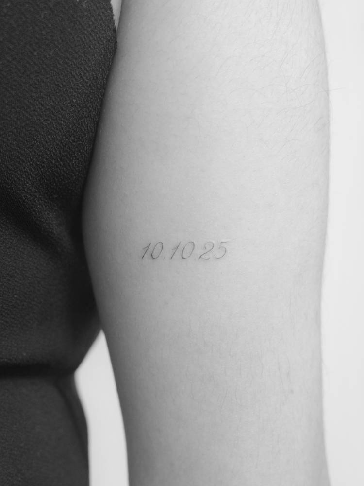 Date "10.10.25" tattoo located on the tricep.
