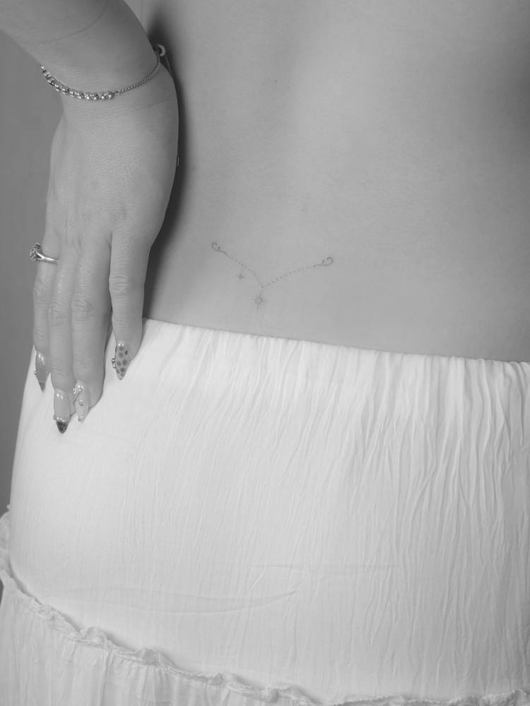 Ornamental design in fine line style tattooed on the lower back.