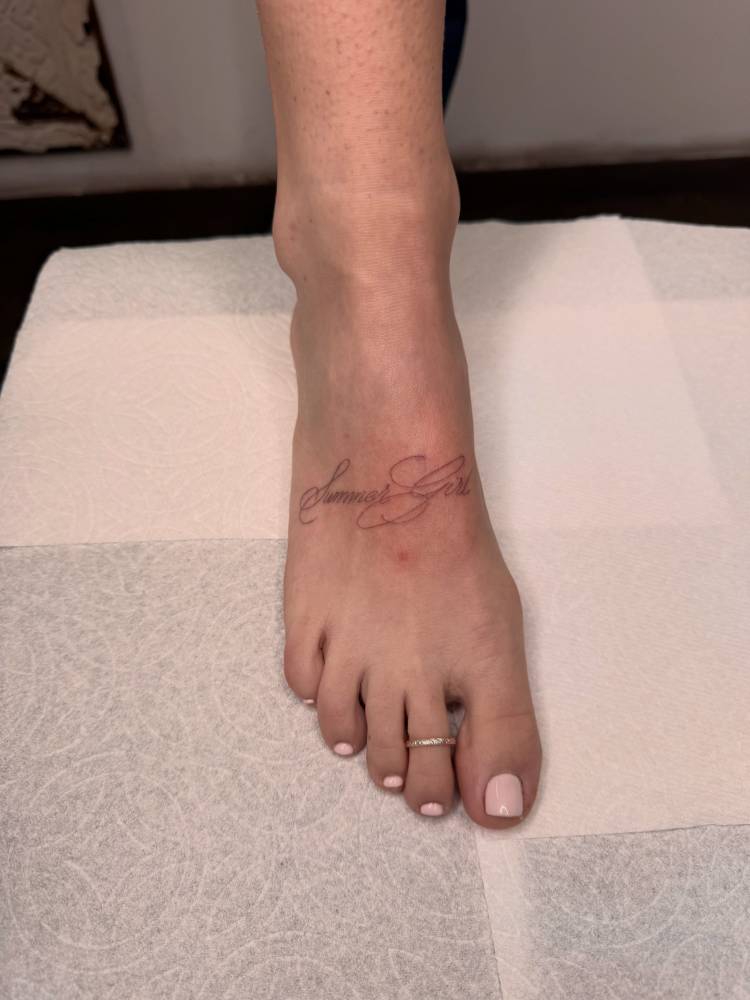 "Summer girl" lettering tattoo located on the foot.