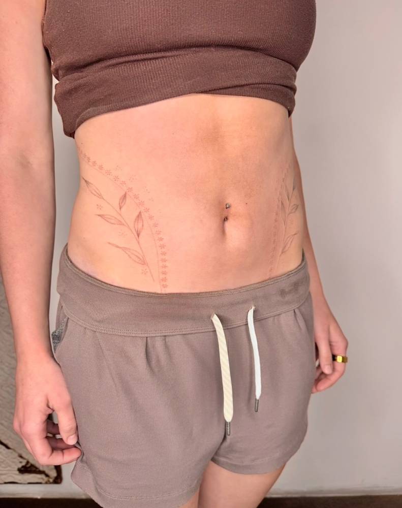 Ornamental leaves tattooed on the waist, fine line style.