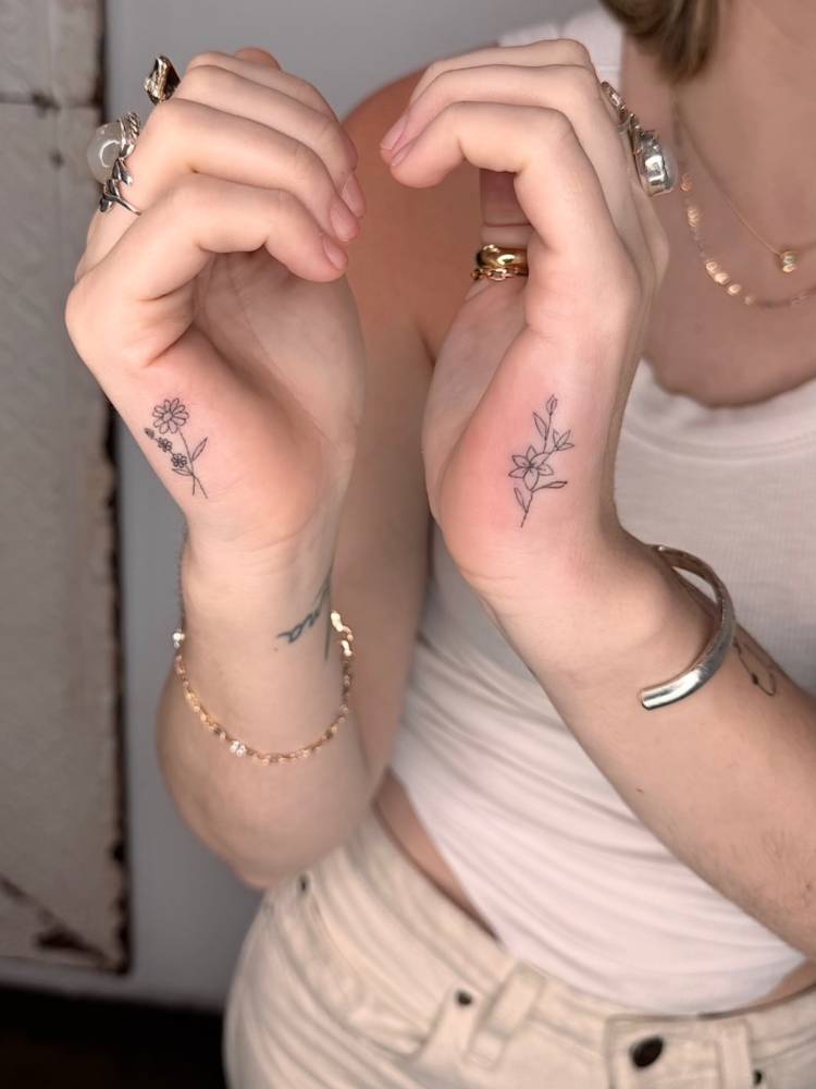 Individual matching little flowers tattooed on the hands.