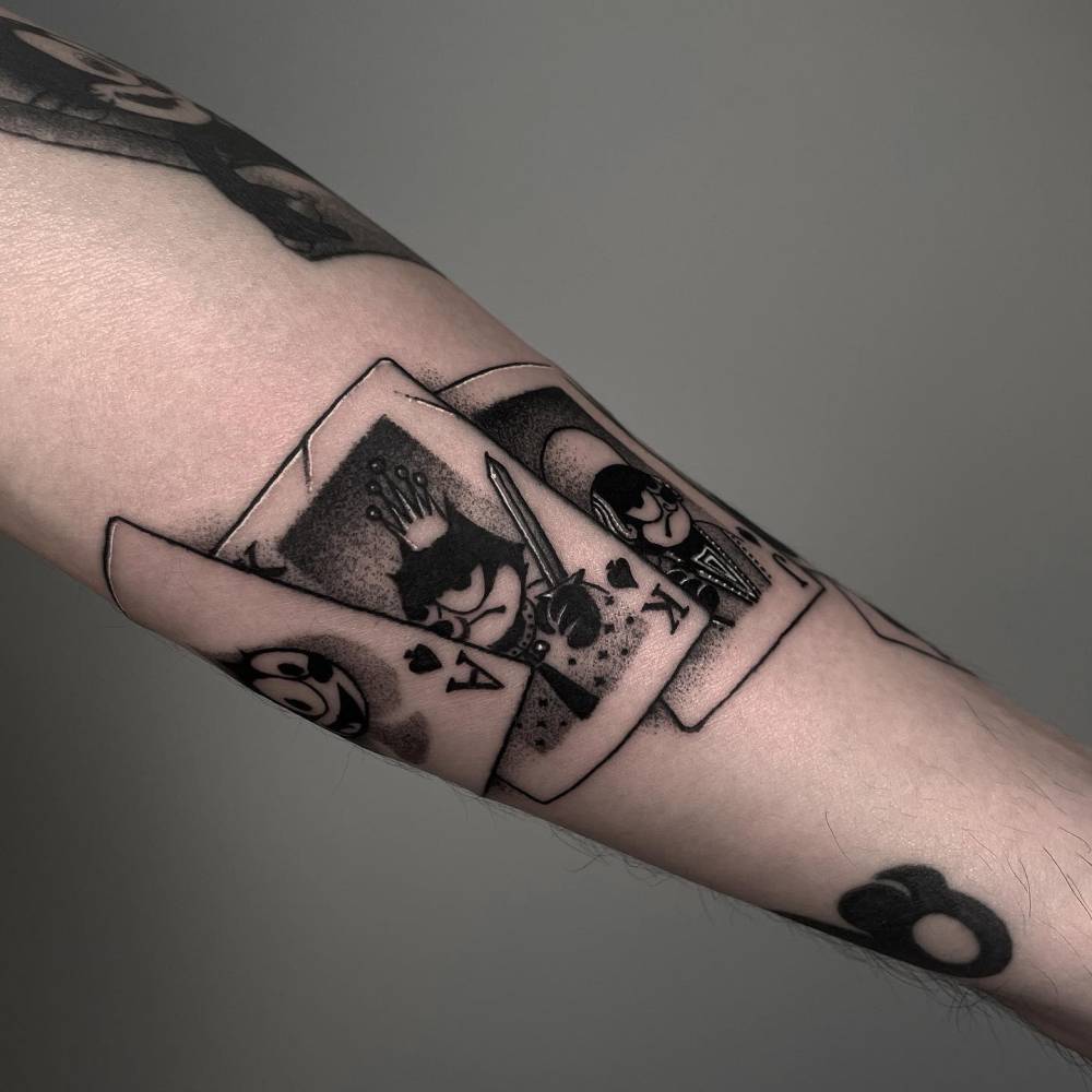 Felix The Cat playing cards tattooed on the inner forearm.