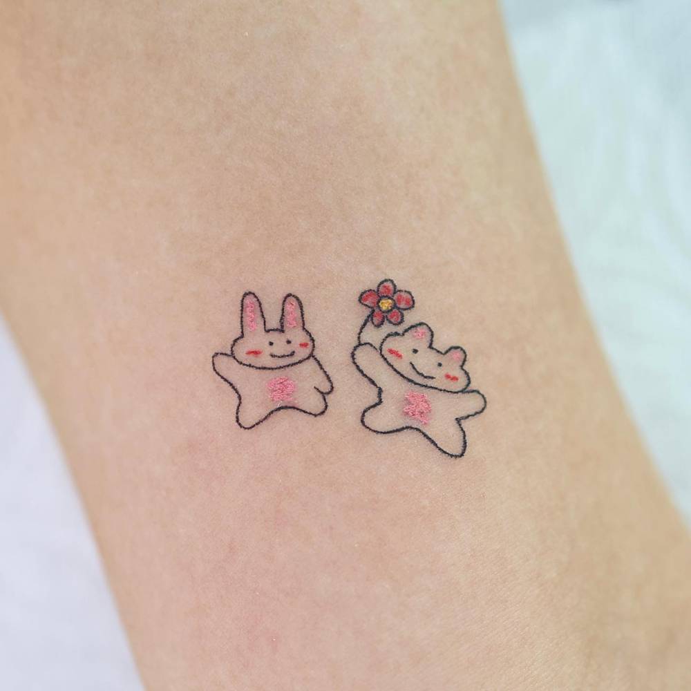 Cartoon style cute rabbits tattoo located on the inner arm.