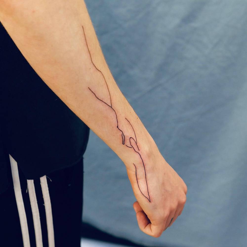 Abstract scribbles tattooed on the forearm and wrist.
