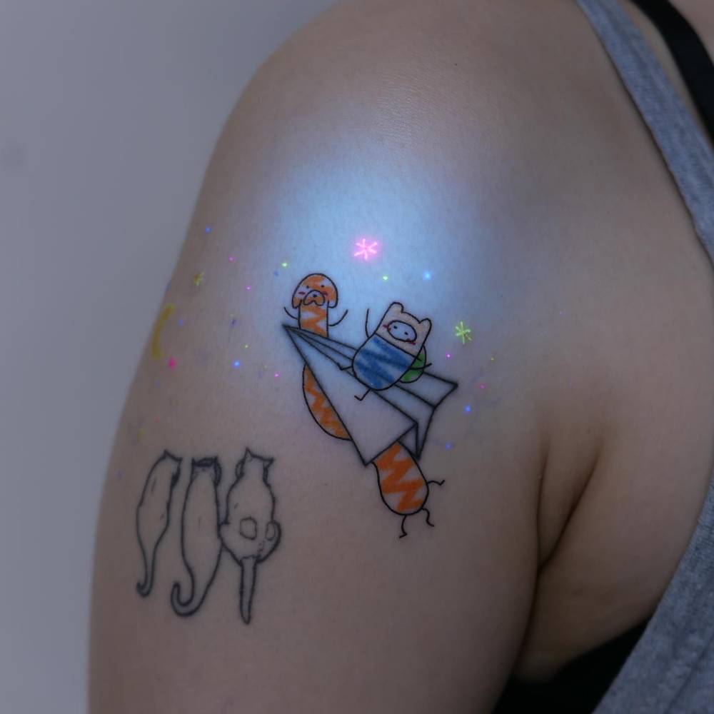 Jake and Finn tattoo in cartoon style located on the upper arm.